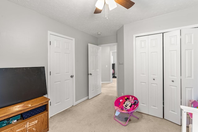 recreation room featuring ceiling fan, light colored carpet, and a textured ceiling