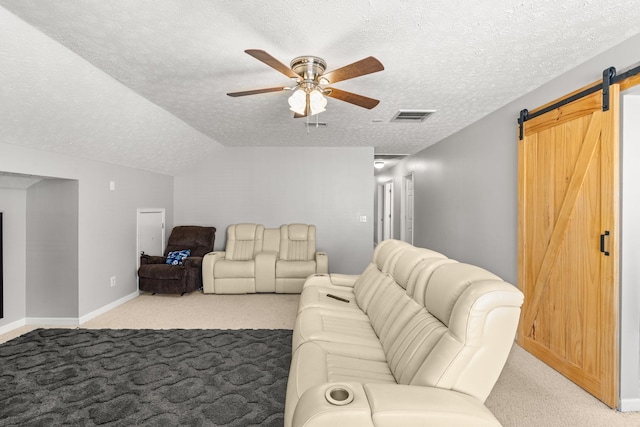 carpeted living room with a textured ceiling, a barn door, ceiling fan, and vaulted ceiling