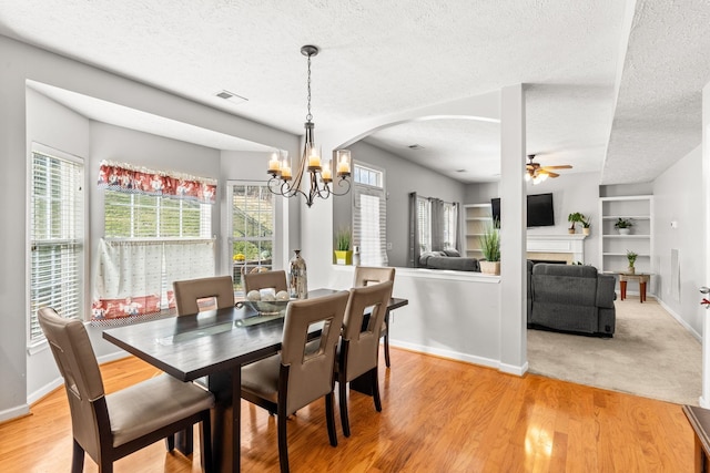 dining room with hardwood / wood-style flooring, ceiling fan with notable chandelier, built in features, and a textured ceiling