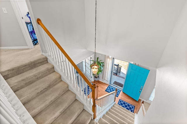 stairs with carpet, a towering ceiling, and a notable chandelier