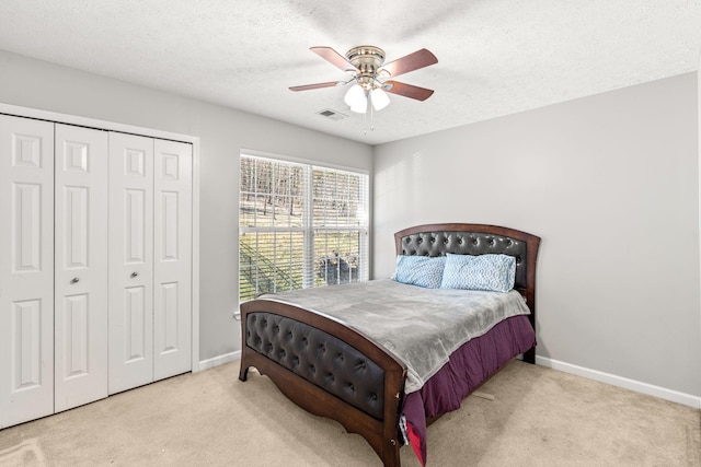 carpeted bedroom featuring a textured ceiling, a closet, and ceiling fan