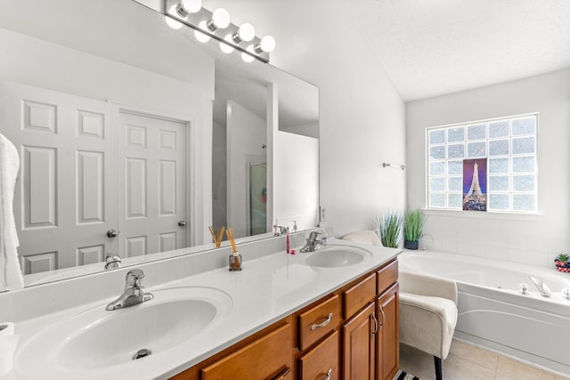 bathroom featuring tile patterned floors, vanity, a bathing tub, and a textured ceiling