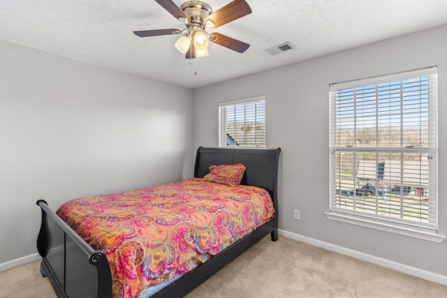 bedroom featuring light carpet, a textured ceiling, and ceiling fan