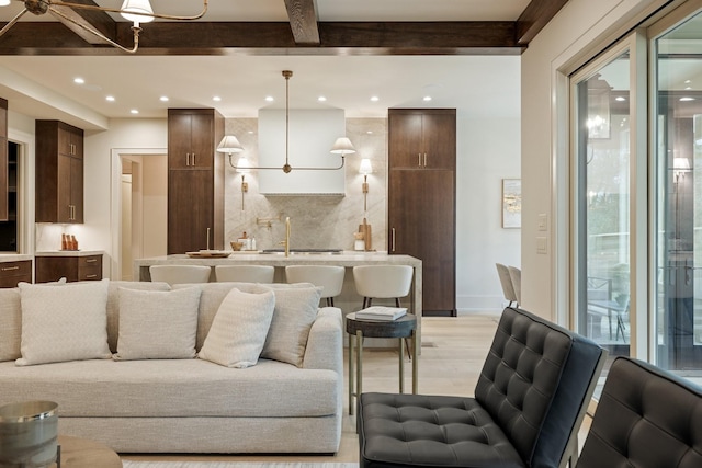 living room with beam ceiling, sink, and light hardwood / wood-style flooring