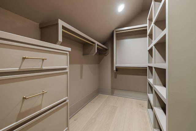 spacious closet with light hardwood / wood-style flooring and lofted ceiling