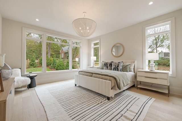 bedroom featuring a chandelier, light wood-type flooring, and multiple windows