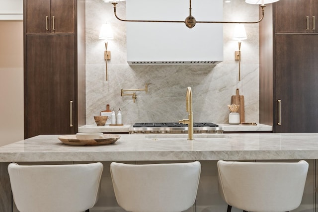 kitchen with decorative backsplash, light stone countertops, sink, and a breakfast bar