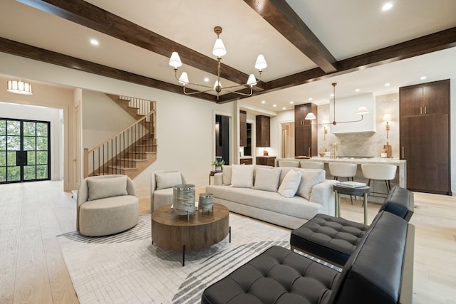 living room featuring beamed ceiling, a chandelier, and light wood-type flooring