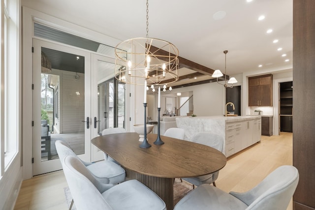 dining space featuring beam ceiling, sink, french doors, light hardwood / wood-style flooring, and a notable chandelier