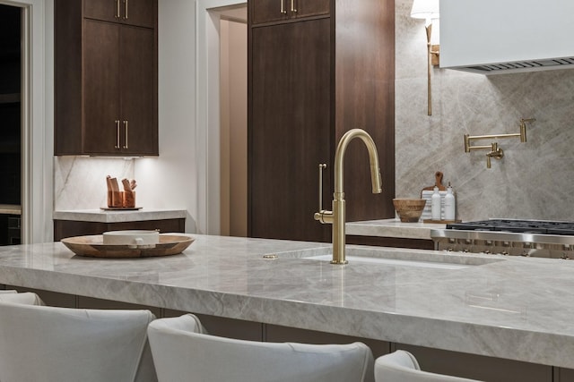 kitchen with dark brown cabinets, a kitchen bar, and tasteful backsplash