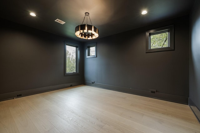 spare room with light wood-type flooring and a notable chandelier