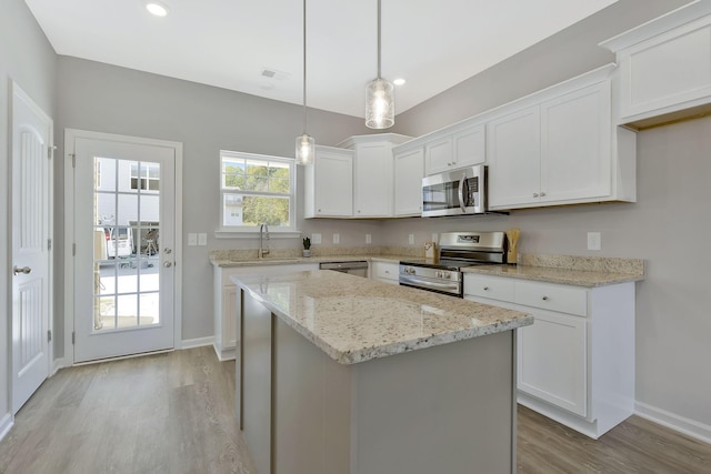 kitchen with a center island, white cabinets, sink, decorative light fixtures, and stainless steel appliances