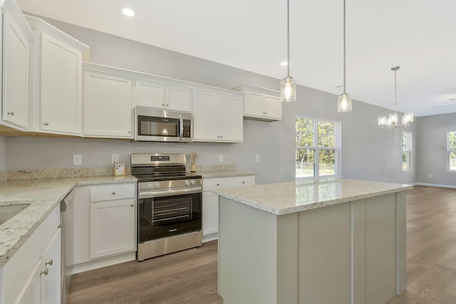 kitchen featuring white cabinets, decorative light fixtures, a center island, and appliances with stainless steel finishes