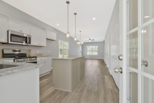 kitchen featuring white cabinetry, ceiling fan, decorative light fixtures, and appliances with stainless steel finishes