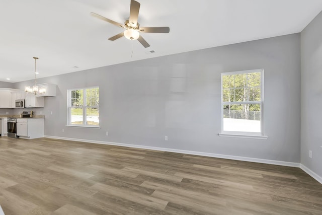 unfurnished living room featuring ceiling fan with notable chandelier and light wood-type flooring