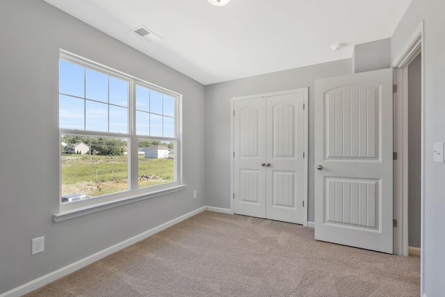 unfurnished bedroom with a closet and light colored carpet