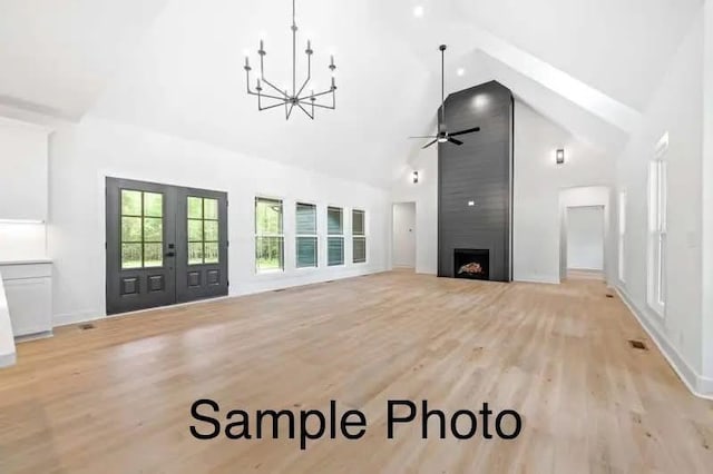 living room featuring light wood finished floors, high vaulted ceiling, a fireplace, ceiling fan, and french doors