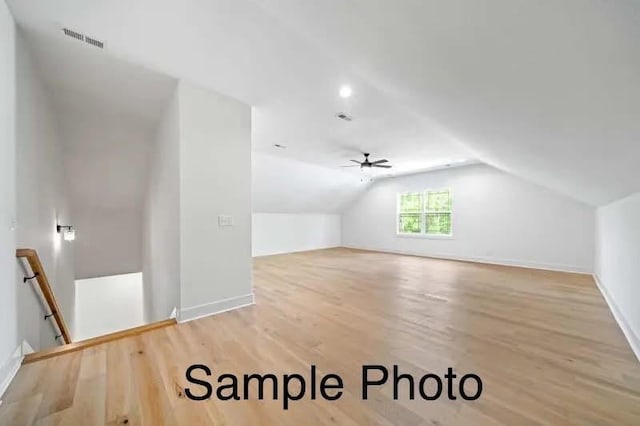 bonus room featuring baseboards, light wood-type flooring, lofted ceiling, and visible vents