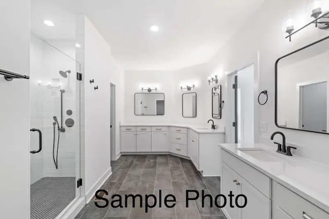 bathroom with a stall shower, two vanities, wood finish floors, and a sink