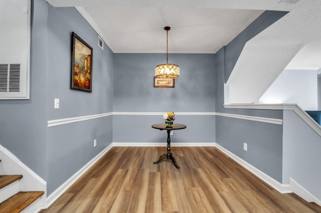 dining space featuring hardwood / wood-style flooring, a textured ceiling, crown molding, and an inviting chandelier