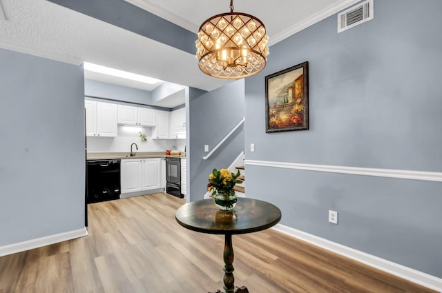 kitchen featuring sink, black appliances, an inviting chandelier, white cabinetry, and hanging light fixtures