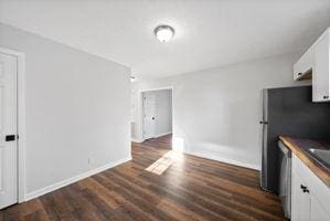 kitchen featuring white cabinetry, dark hardwood / wood-style flooring, and stainless steel dishwasher