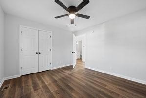 unfurnished bedroom featuring dark hardwood / wood-style flooring, a closet, and ceiling fan