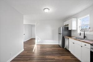 kitchen featuring sink, white cabinets, stainless steel dishwasher, and dark hardwood / wood-style floors