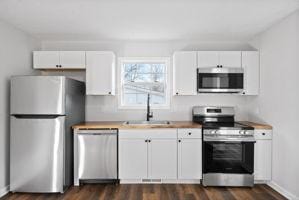 kitchen with dark hardwood / wood-style flooring, stainless steel appliances, white cabinetry, and sink