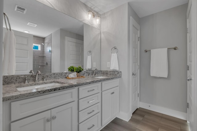 bathroom with a tile shower and vanity