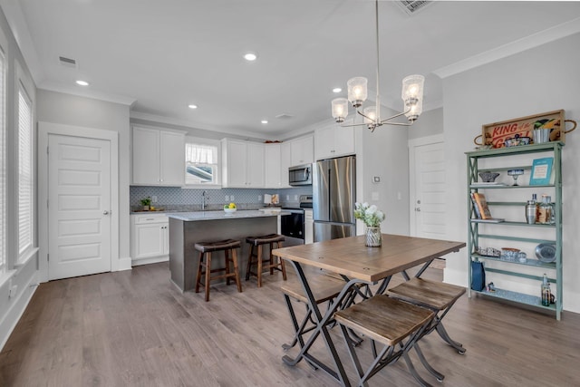 dining area featuring crown molding, sink, a chandelier, and light wood-type flooring