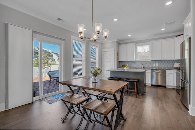 dining room with a chandelier, crown molding, sink, and dark wood-type flooring