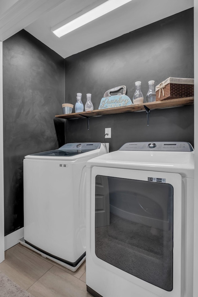 laundry area with separate washer and dryer and light tile patterned floors