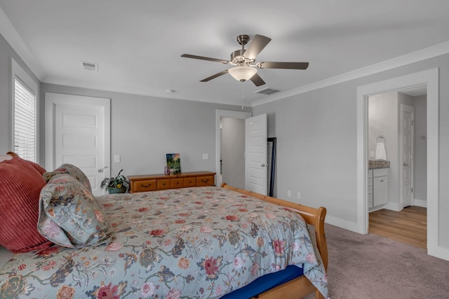 bedroom featuring light carpet, ensuite bath, ceiling fan, and crown molding