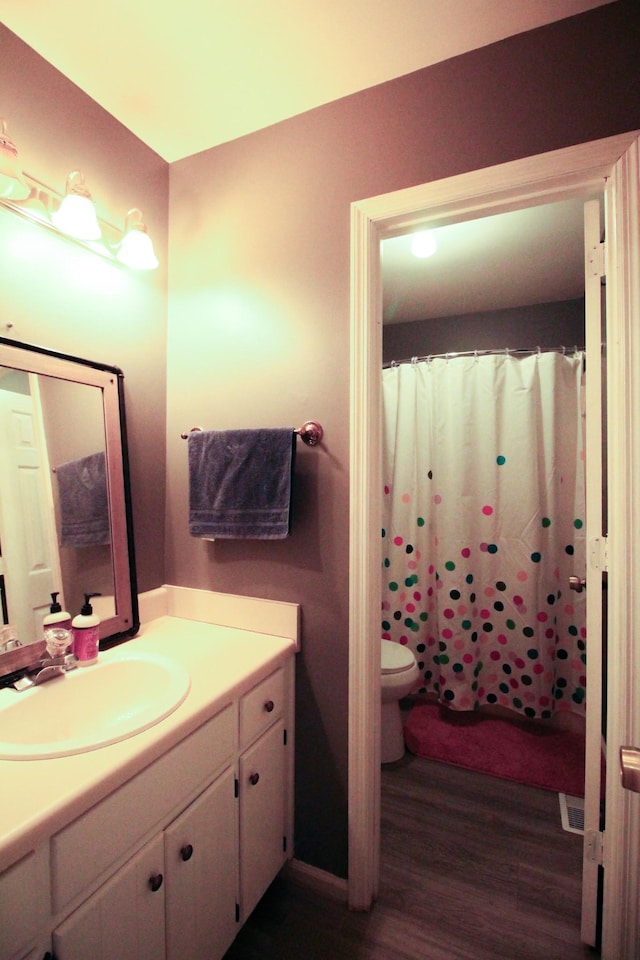 bathroom featuring wood-type flooring, curtained shower, vanity, and toilet