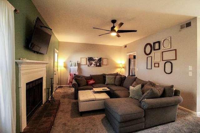 living room featuring ceiling fan, a tiled fireplace, and dark carpet