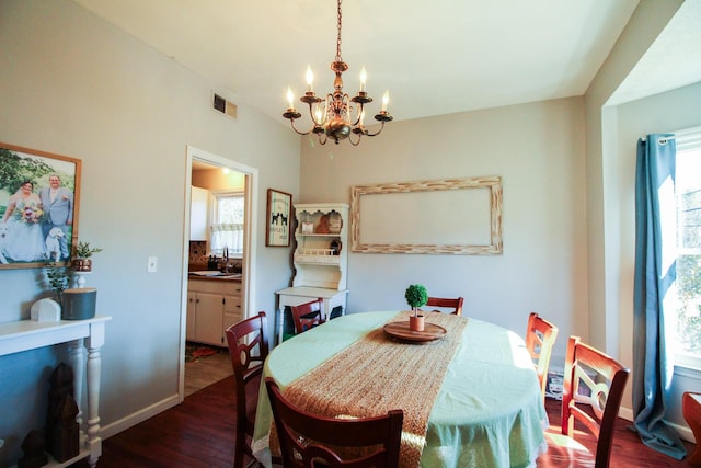 dining space with an inviting chandelier, sink, dark wood-type flooring, and a healthy amount of sunlight