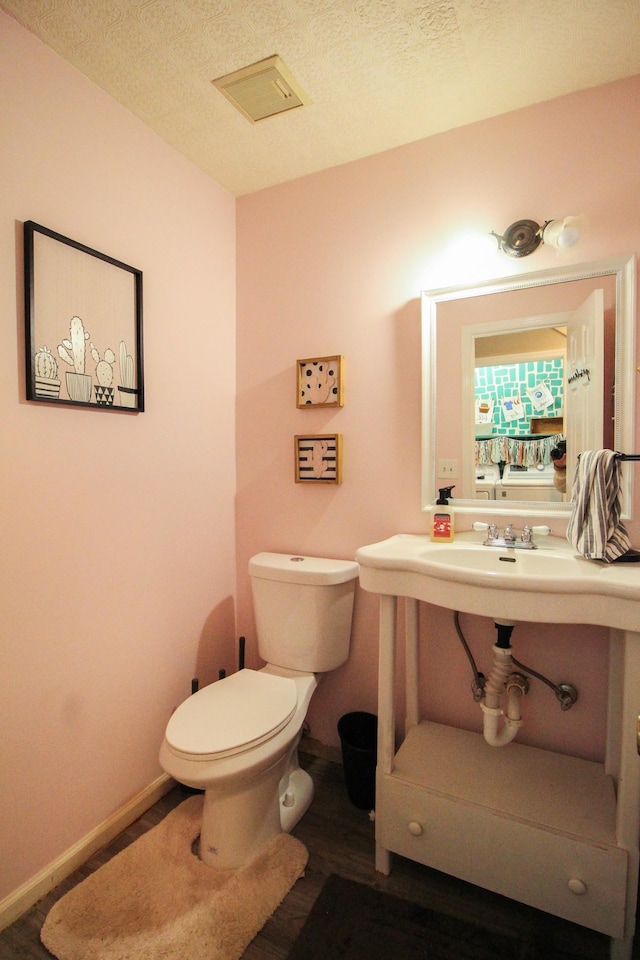 bathroom with hardwood / wood-style flooring, a textured ceiling, and toilet