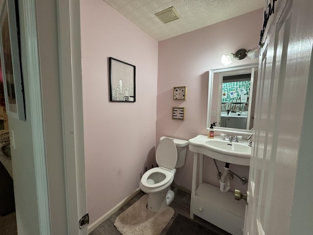 bathroom with sink, a textured ceiling, and toilet