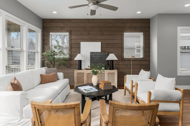 living room with ceiling fan and wood walls