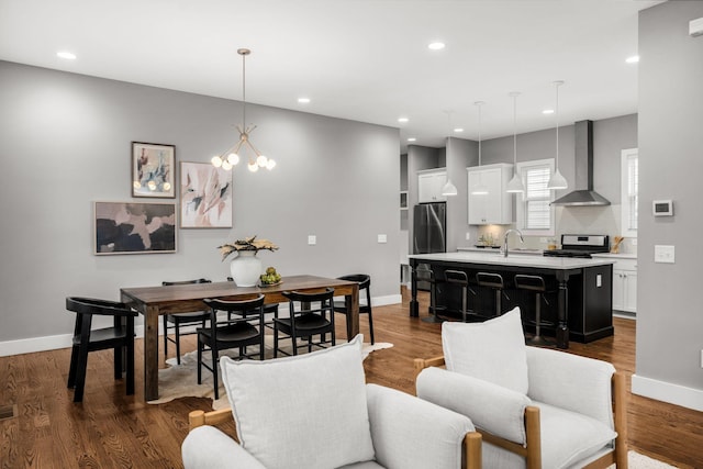 dining area with dark hardwood / wood-style flooring, an inviting chandelier, and sink