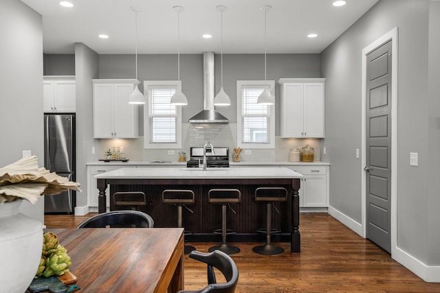 kitchen with pendant lighting, a kitchen island with sink, white cabinets, a kitchen breakfast bar, and appliances with stainless steel finishes