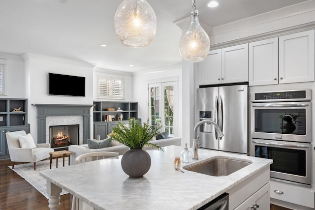 kitchen featuring appliances with stainless steel finishes, dark hardwood / wood-style flooring, ornamental molding, sink, and pendant lighting