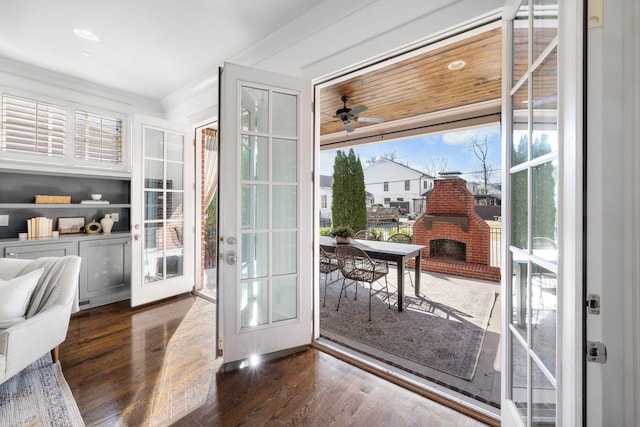 doorway to outside featuring a brick fireplace, ceiling fan, dark hardwood / wood-style flooring, and french doors