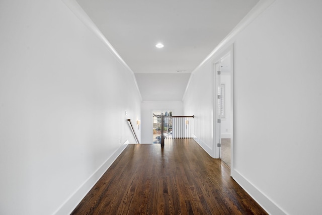 corridor with dark hardwood / wood-style floors, vaulted ceiling, and ornamental molding