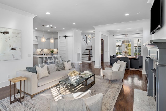 living room featuring hardwood / wood-style floors, a barn door, ornamental molding, and sink