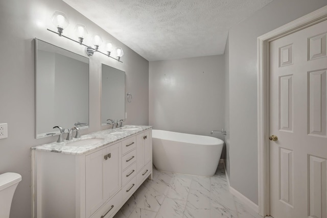 bathroom with a tub to relax in, vanity, a textured ceiling, and toilet