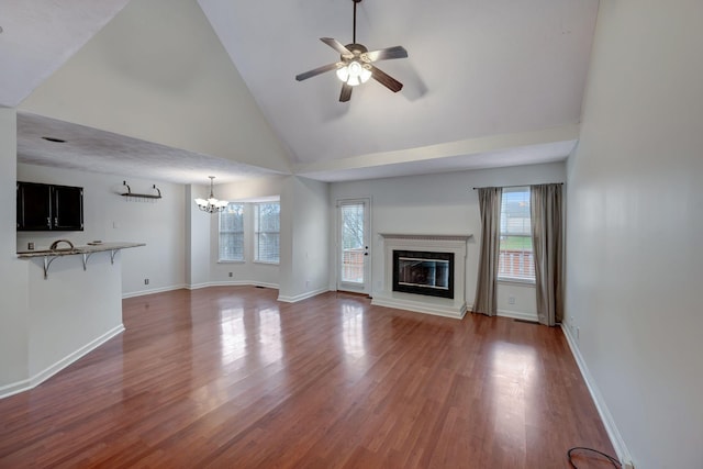 unfurnished living room featuring ceiling fan with notable chandelier, dark hardwood / wood-style flooring, and high vaulted ceiling