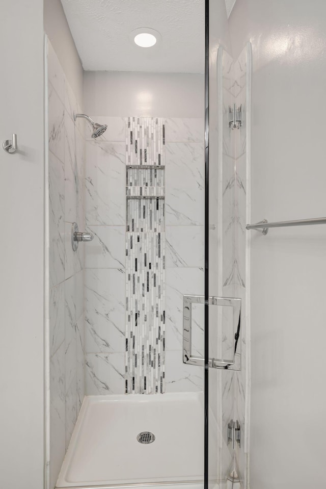 bathroom featuring a tile shower and a textured ceiling