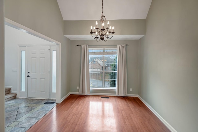 entrance foyer with light hardwood / wood-style floors, vaulted ceiling, and an inviting chandelier